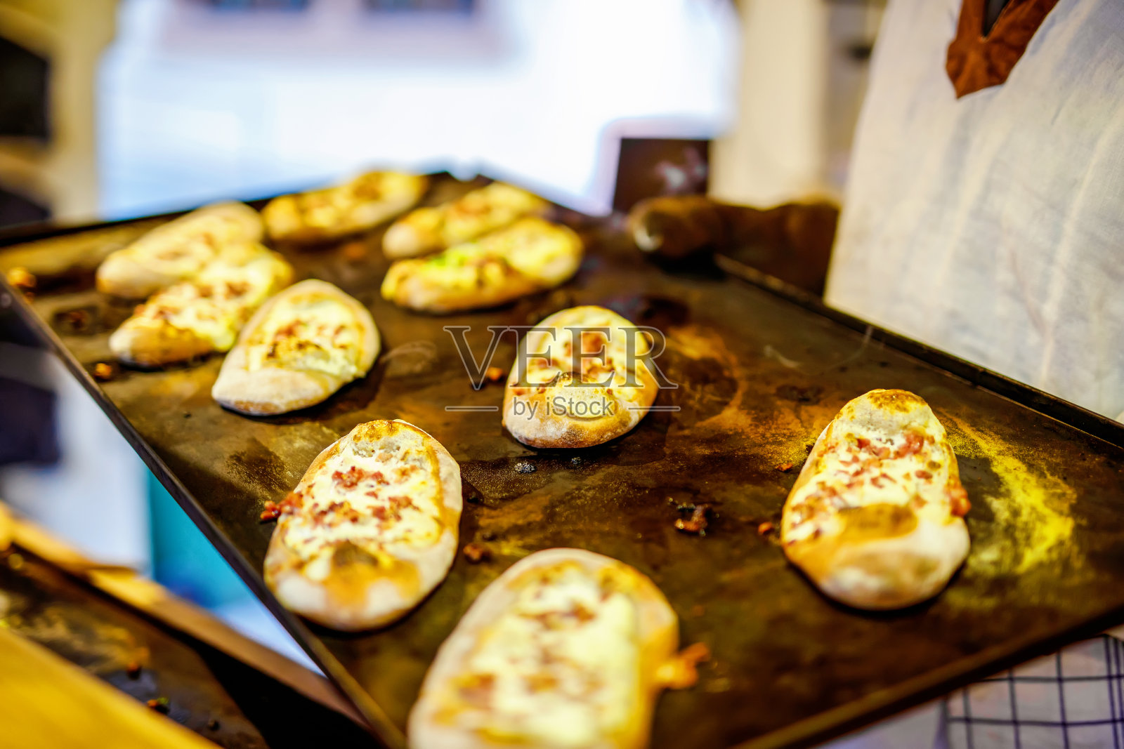 德国圣诞市场上的传统面包配酸奶油和火腿。特写的新鲜烤椒盐卷饼和手在德国的圣诞集市照片摄影图片