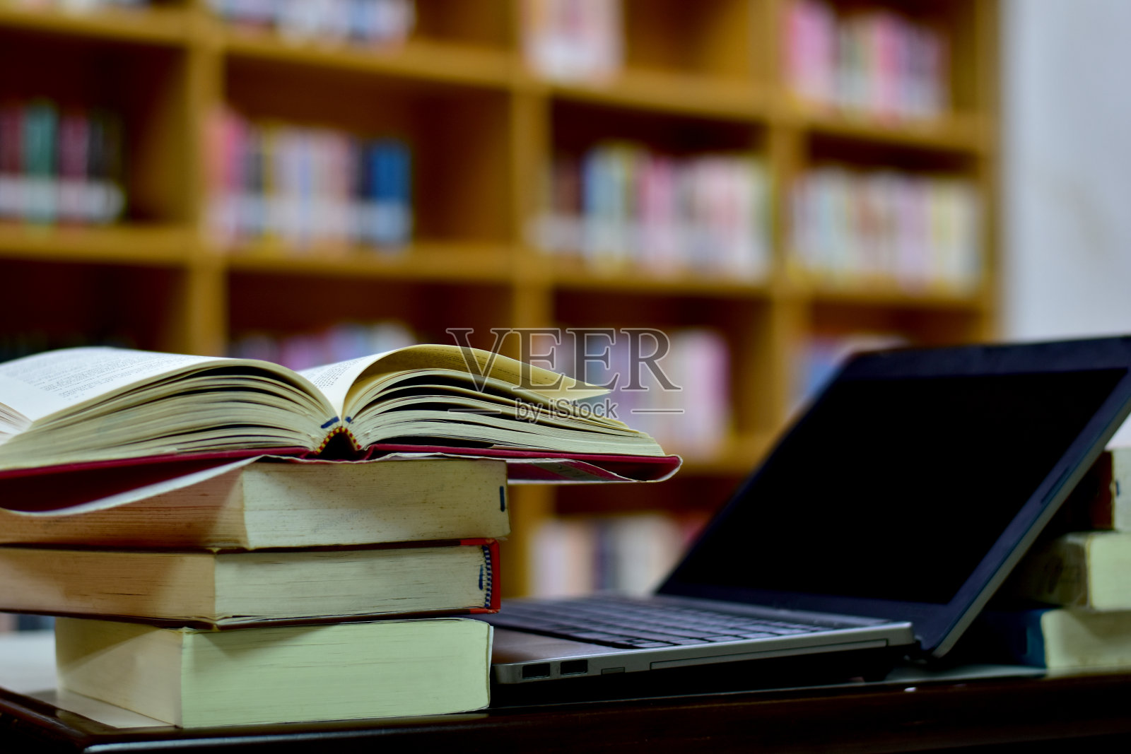 书在木桌上和模糊的书架在图书馆，教育背景，回到学校的概念。照片摄影图片