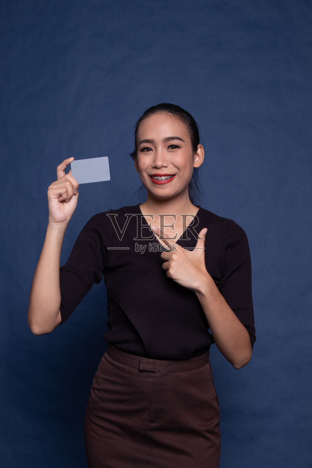 年轻的亚洲女子指着一张空白卡片。照片摄影图片