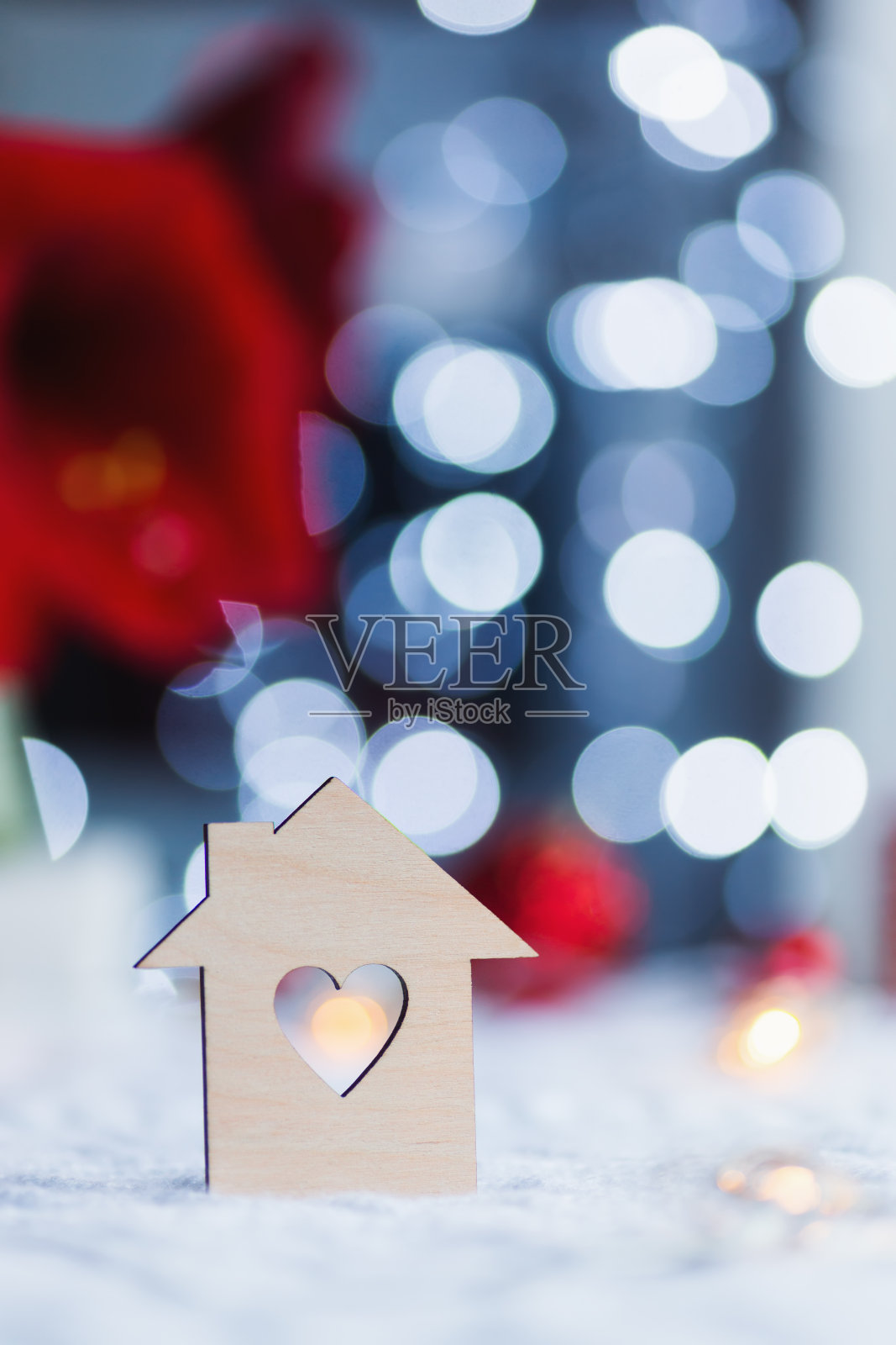 房子的木制图标，心形的洞，红色的家庭圣诞装饰和模糊的散景背景在白天。照片摄影图片