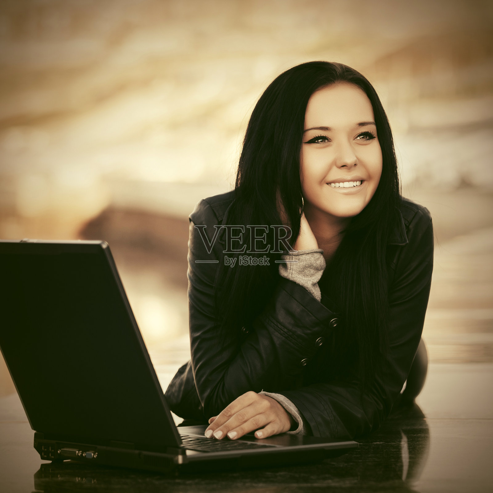 快乐的年轻女子用笔记本电脑躺在栏杆上照片摄影图片