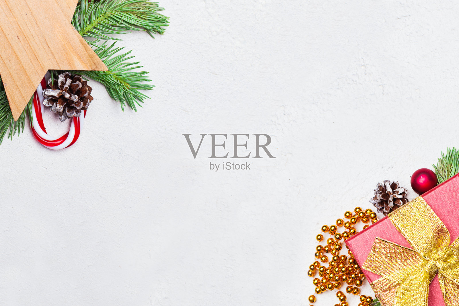 圣诞礼物，绿色的圣诞冷杉枝，红色的冬青浆果和小玩意在白色的灰泥石膏纹理背景。圣诞作文，俯视图平铺与复制空间照片摄影图片