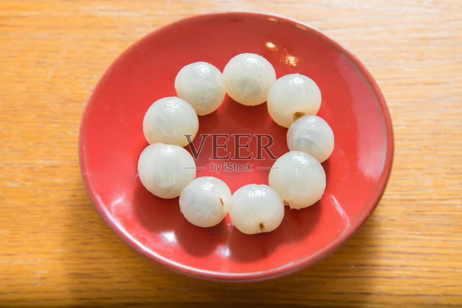 剥去龙眼，置于红瓷盘上孤立照片摄影图片