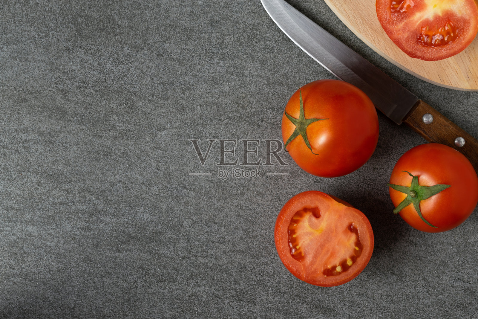 一组用刀和木板切成薄片的西红柿放在水泥桌上。照片摄影图片