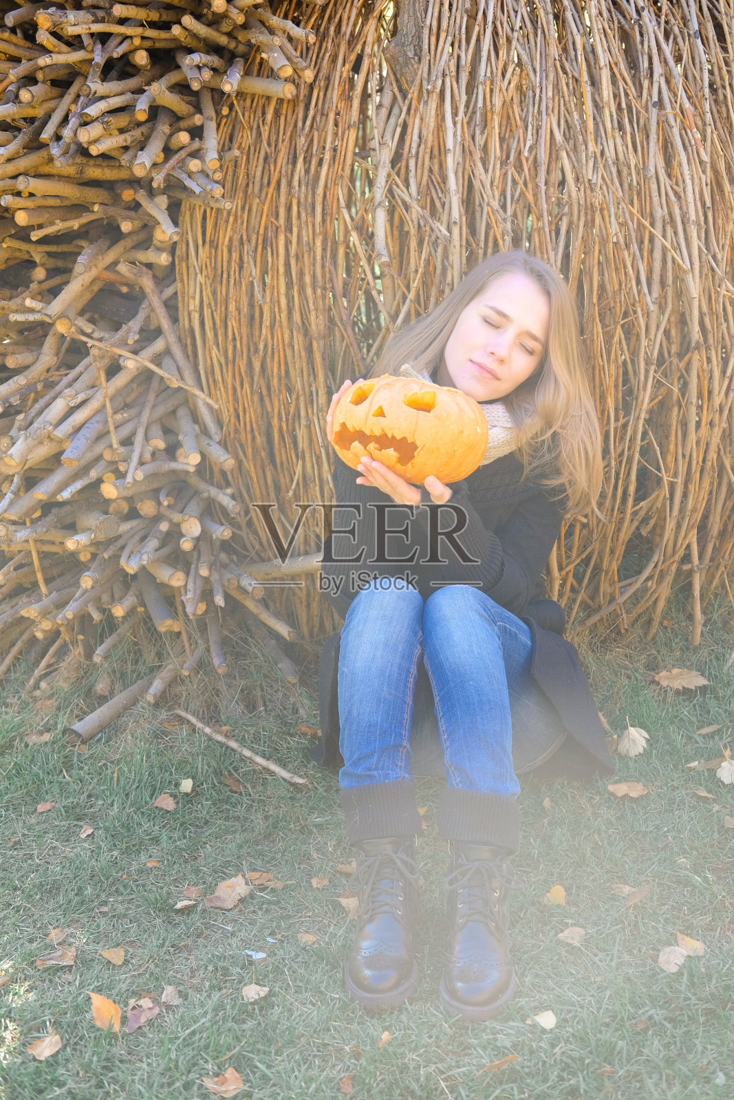 森林里抱着南瓜的女人。南瓜灯-万圣节的装饰。照片摄影图片