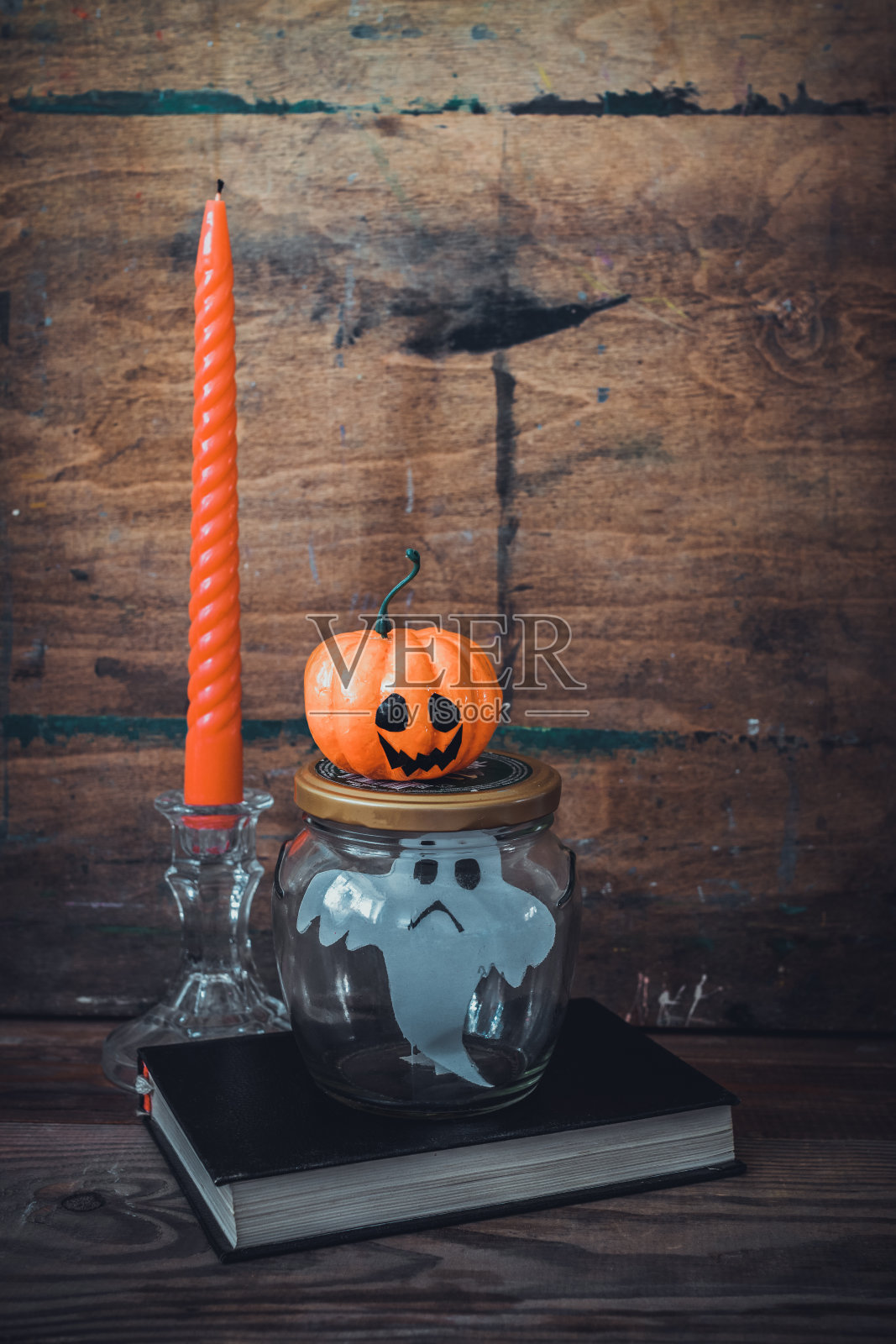 玻璃罐里的纸鬼和蜡烛旁的滑稽南瓜。是时候庆祝万圣节了。照片摄影图片