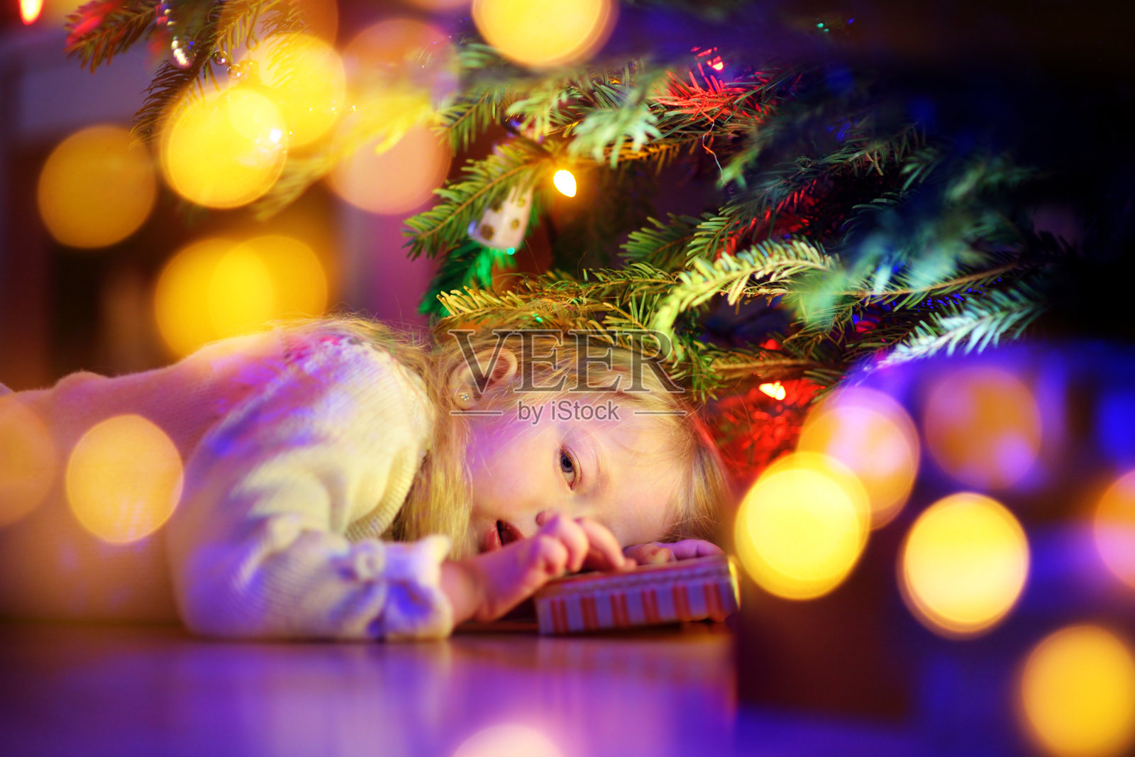 可爱的小女孩在圣诞树下寻找礼物照片摄影图片