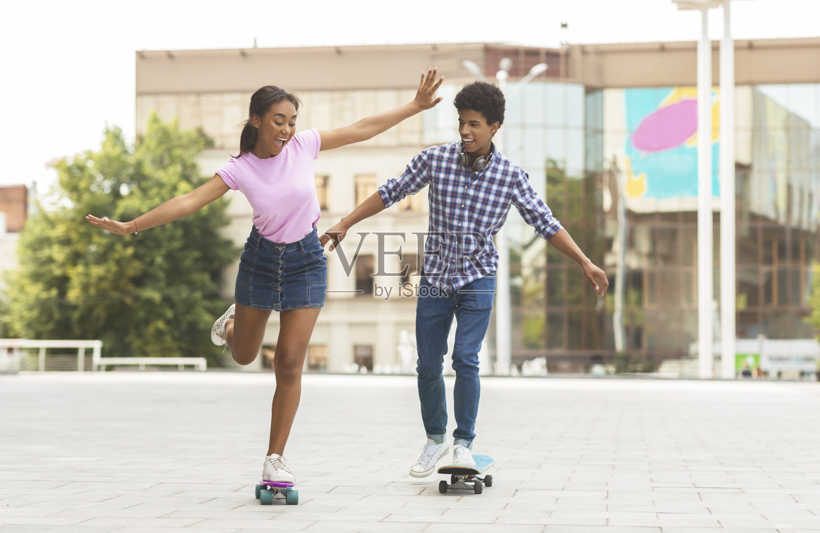 快乐的青少年夫妇骑着现代巡洋舰滑板在城市街道上照片摄影图片