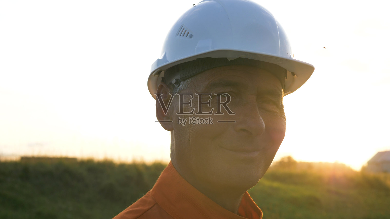 在现代智能手机上穿着橙色连身裤的老测量员照片摄影图片