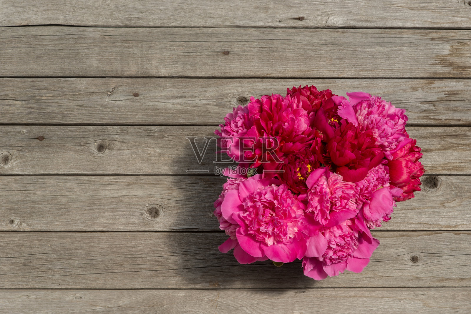 木板上有一束粉红色的牡丹。照片摄影图片