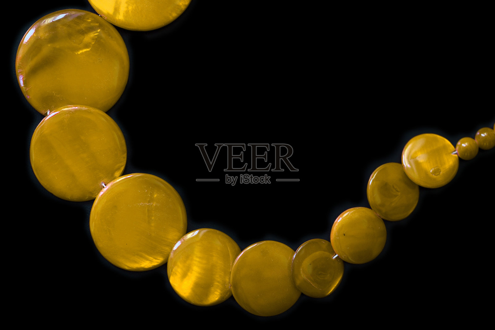 黄色的圆扁珠项链在黑暗的背景上近距离照片摄影图片