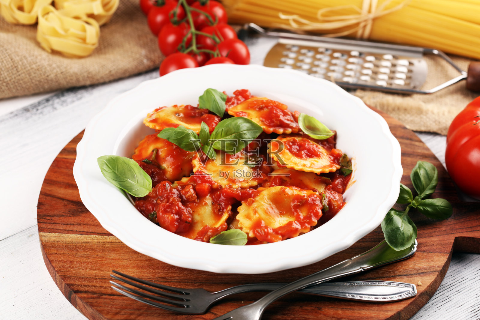 乡村餐桌上的番茄酱意大利饺子，配上帕尔玛干酪和罗勒照片摄影图片