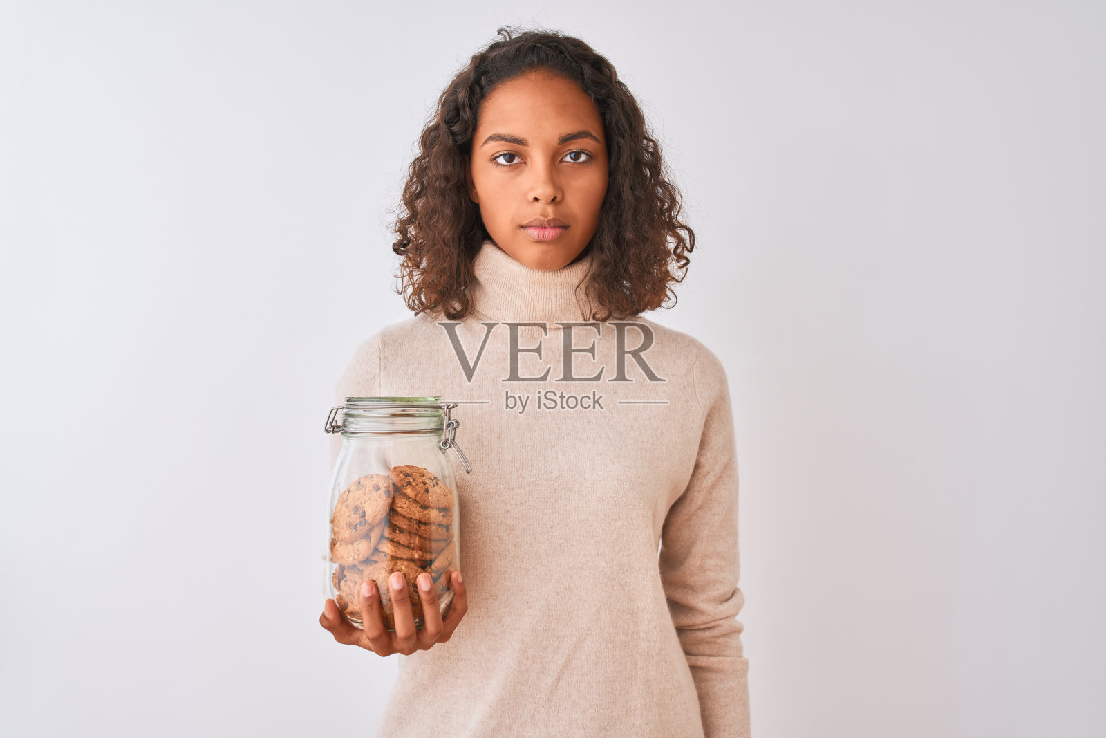 年轻的巴西女子拿着一罐饼干站在孤立的白色背景与自信的表情在聪明的脸上思考严肃照片摄影图片