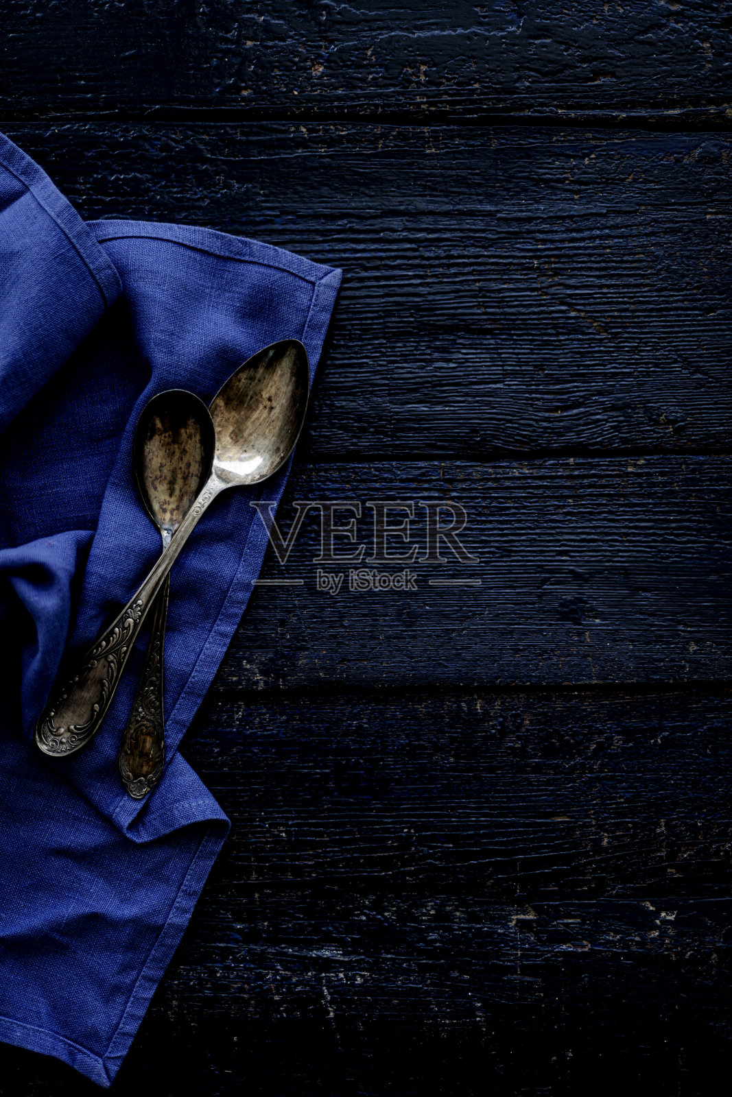 古老的餐具勺子在一个古老的木制深蓝色背景。有选择性的重点。照片摄影图片