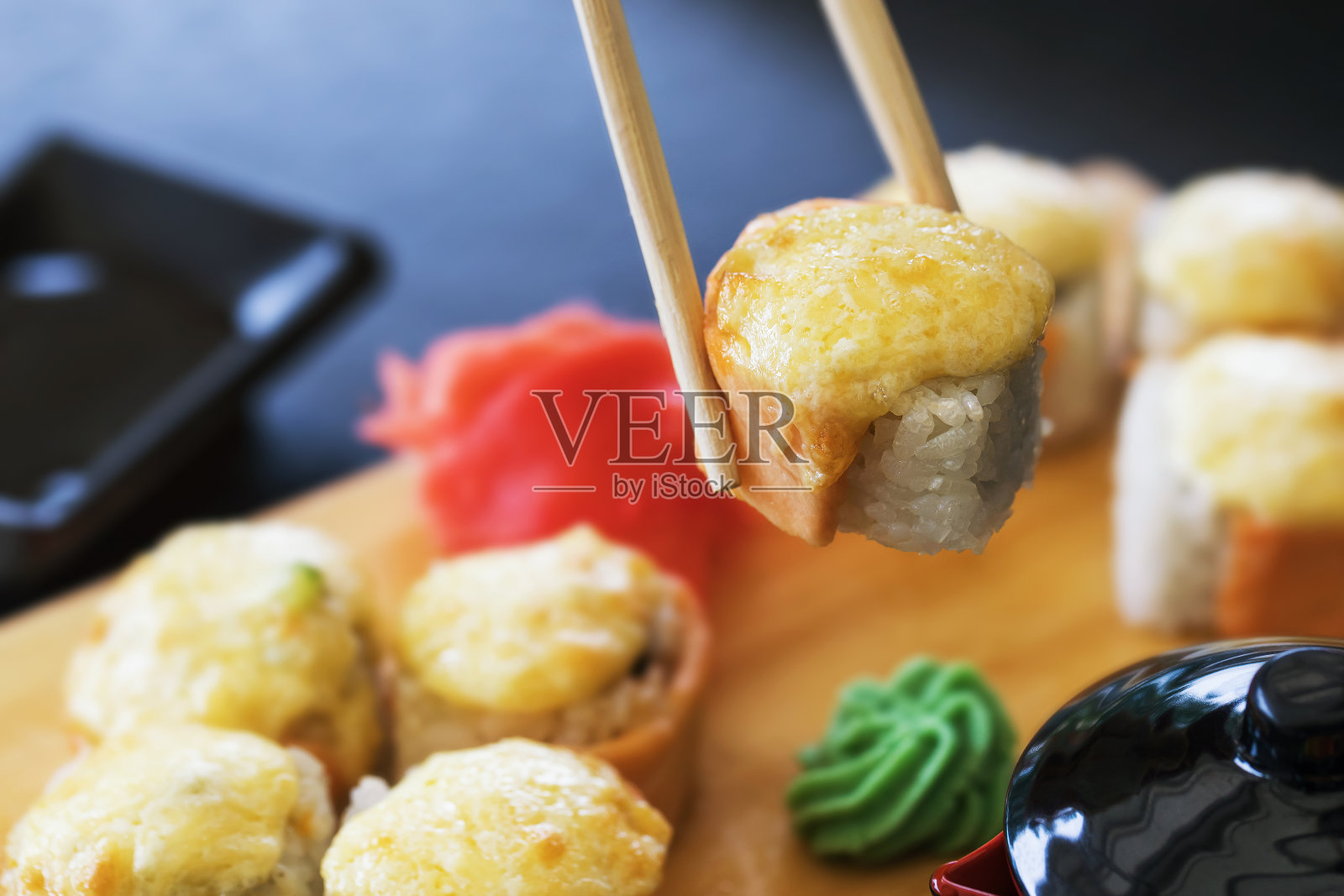 热卷与生姜，芥末和鲑鱼在一个木制摊位的特写。美味的日本菜照片摄影图片