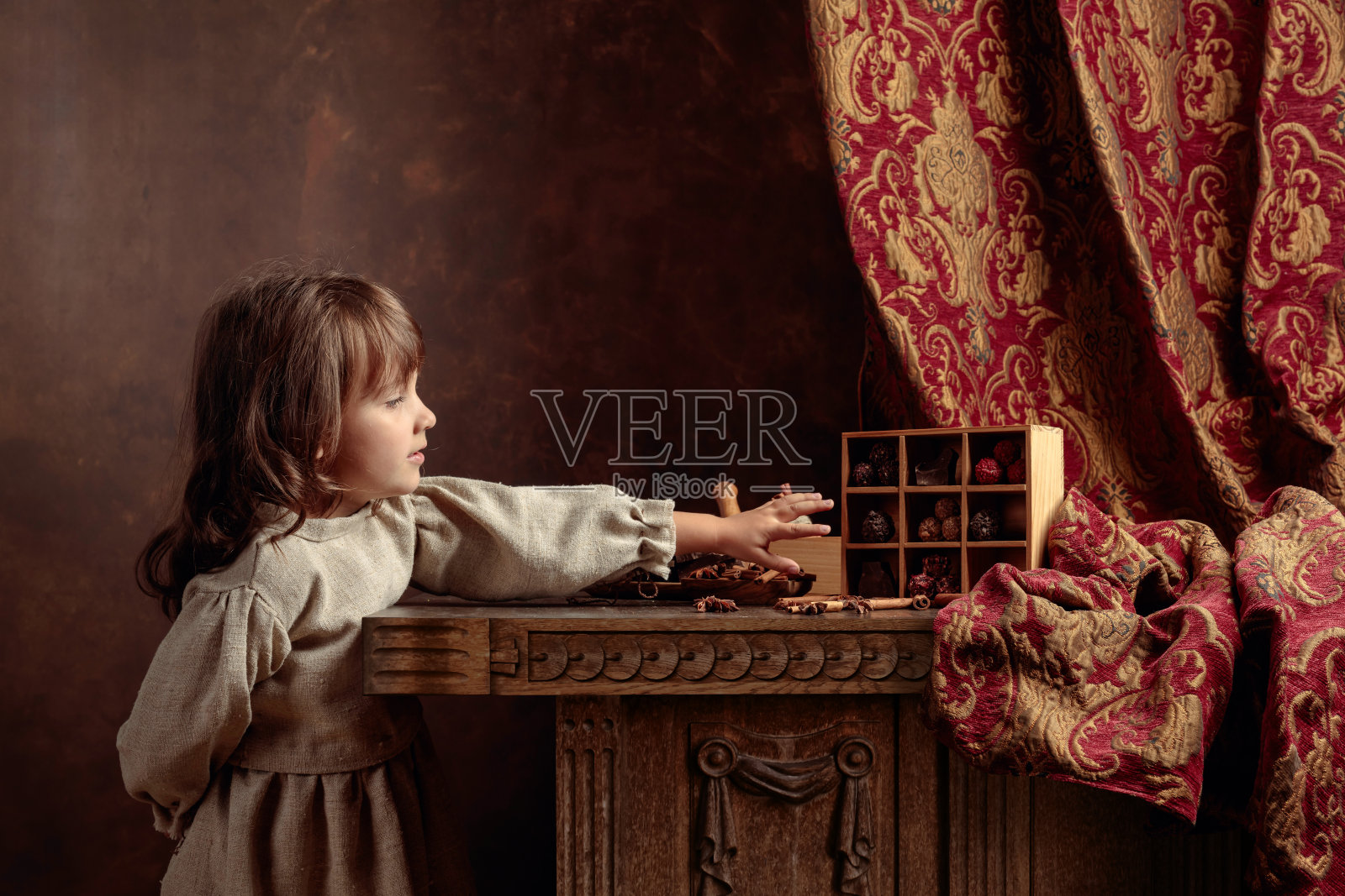 一个穿着复古亚麻布裙子的小女孩，旁边放着糖果。体裁肖像在复古风格。照片摄影图片