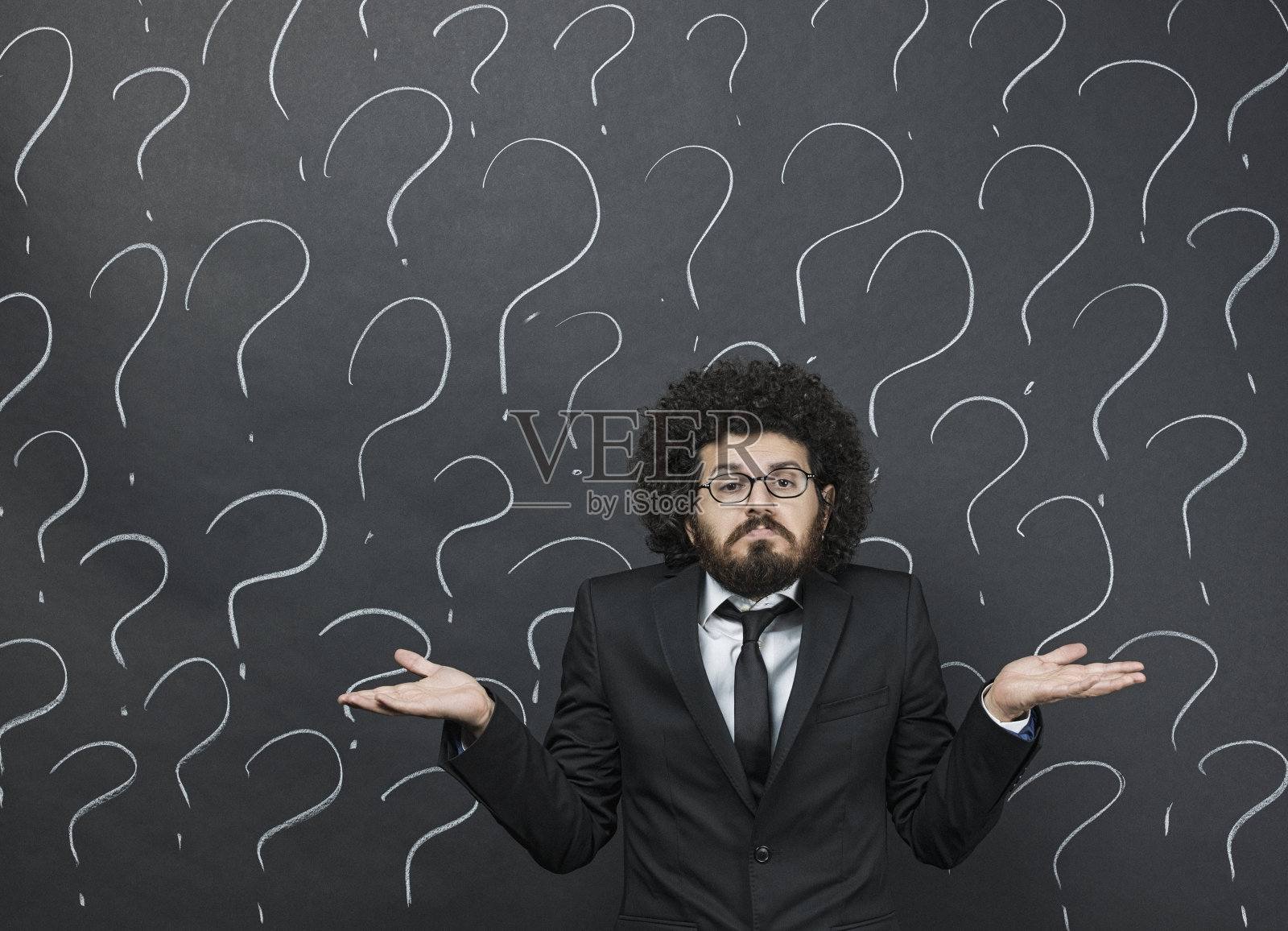 困惑的男商人站在写满问号的黑板前照片摄影图片