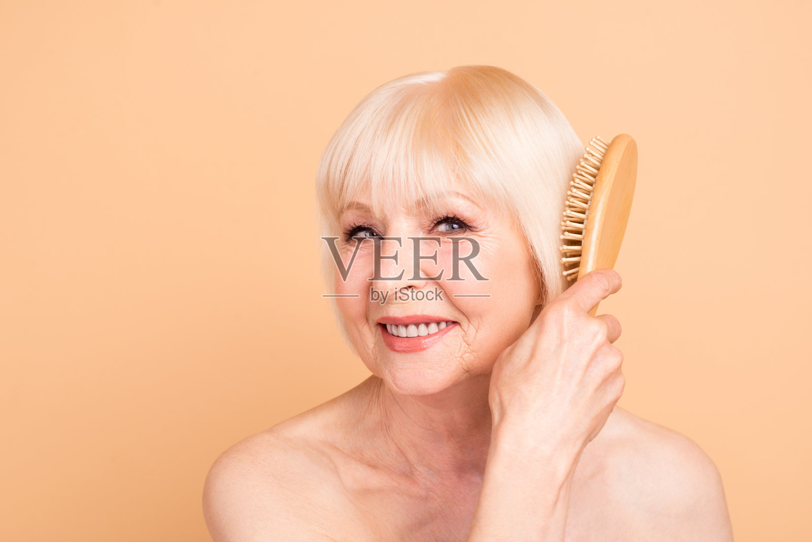 她的特写肖像，她很好，有吸引力，可爱的，，精心打扮，愉快愉快，灰色头发的女士梳理时间，为自己孤立的米色背景照片摄影图片