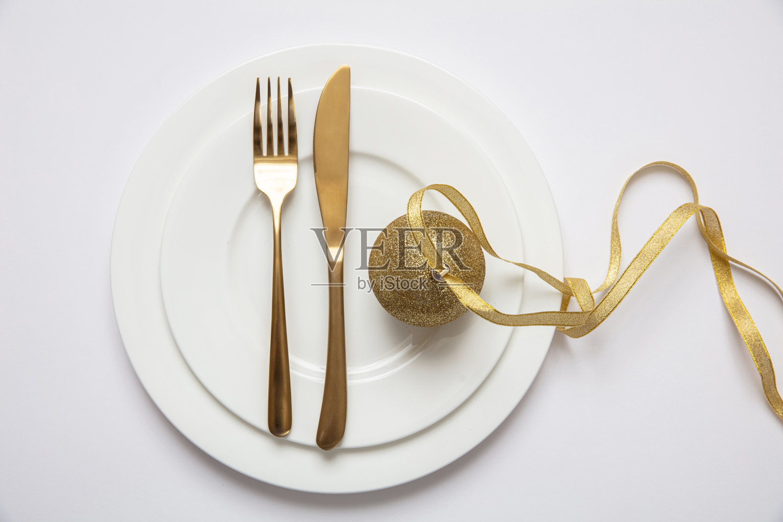 餐桌摆设，圣诞，新年。白色餐具上的金色餐具，白色背景照片摄影图片