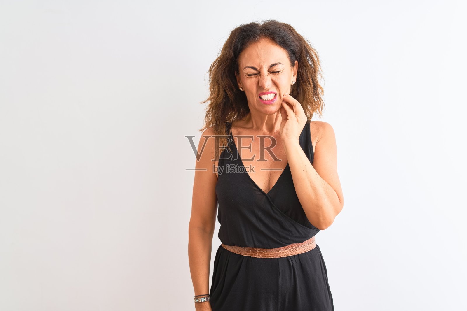 中年妇女穿着黑色休闲服站在孤立的白色背景与手触摸嘴痛苦的表情，因为牙痛或牙齿疾病的牙齿。牙医的概念。照片摄影图片