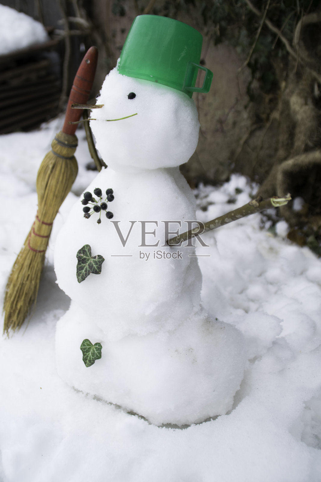 有扫帚和绿色塑料帽的小雪人照片摄影图片
