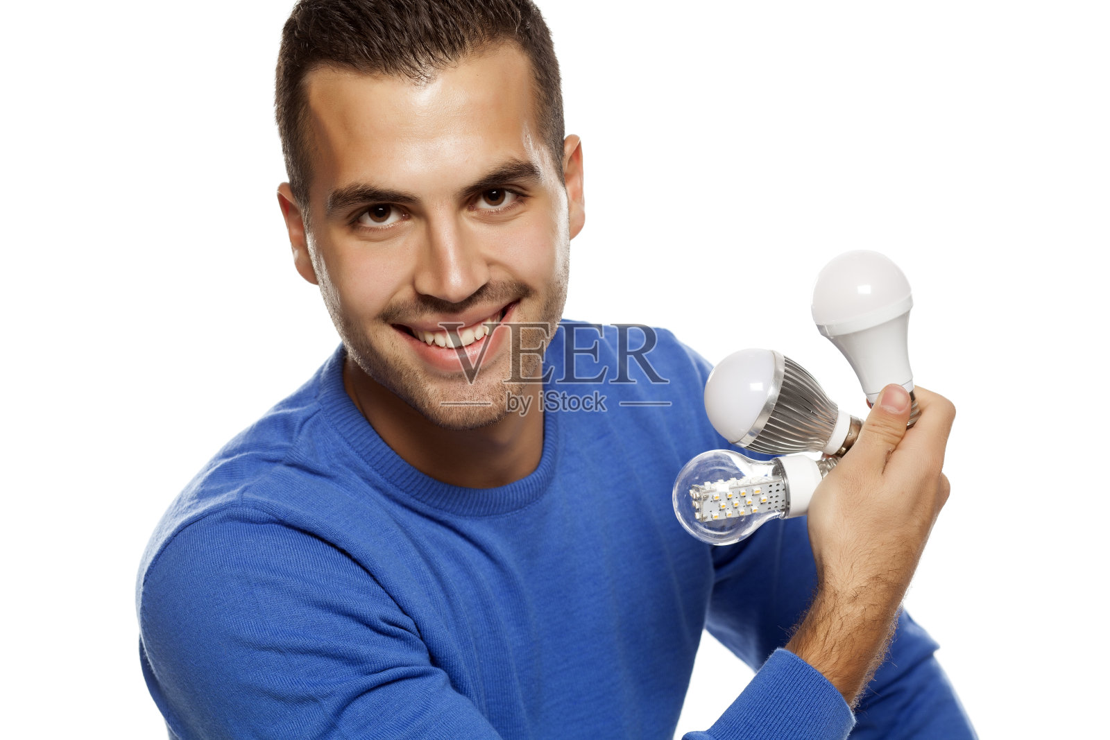 一个快乐的年轻人的肖像，在白色的背景上拿着三个不同的LED灯泡照片摄影图片