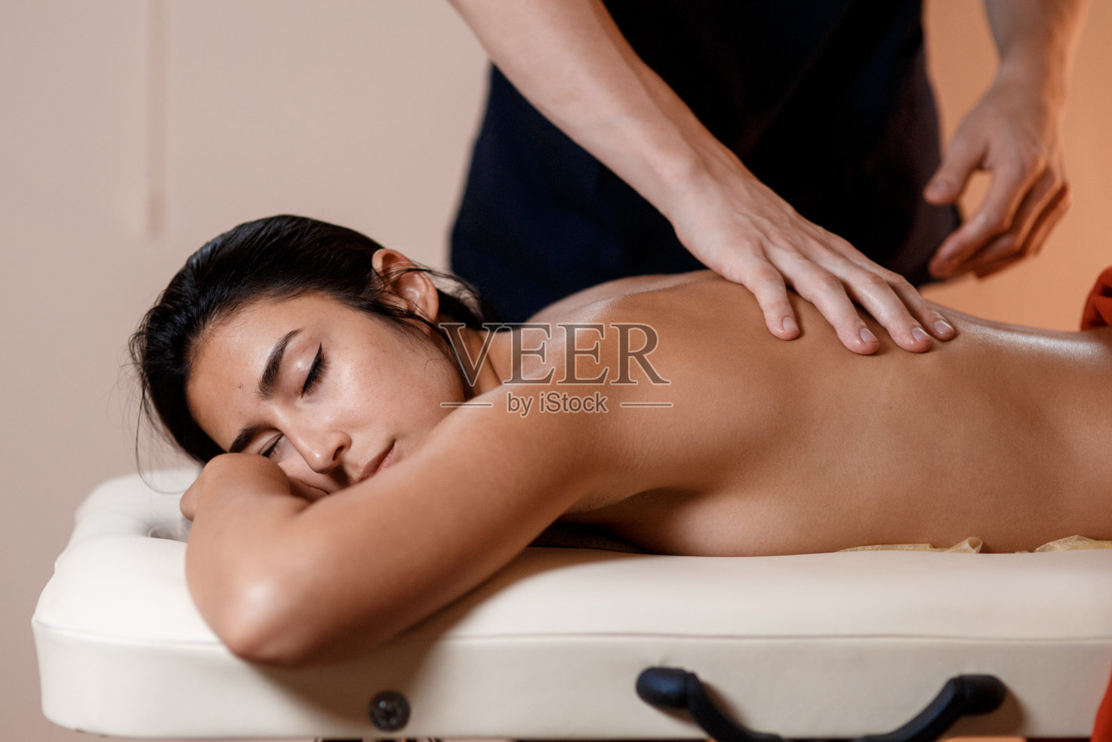 一位年轻女子接受按摩。按摩师做背部按摩照片摄影图片