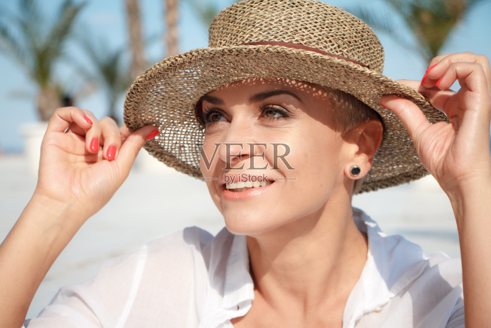 可爱的年轻女子，短发，戴着沙滩帽在海滩上照片摄影图片