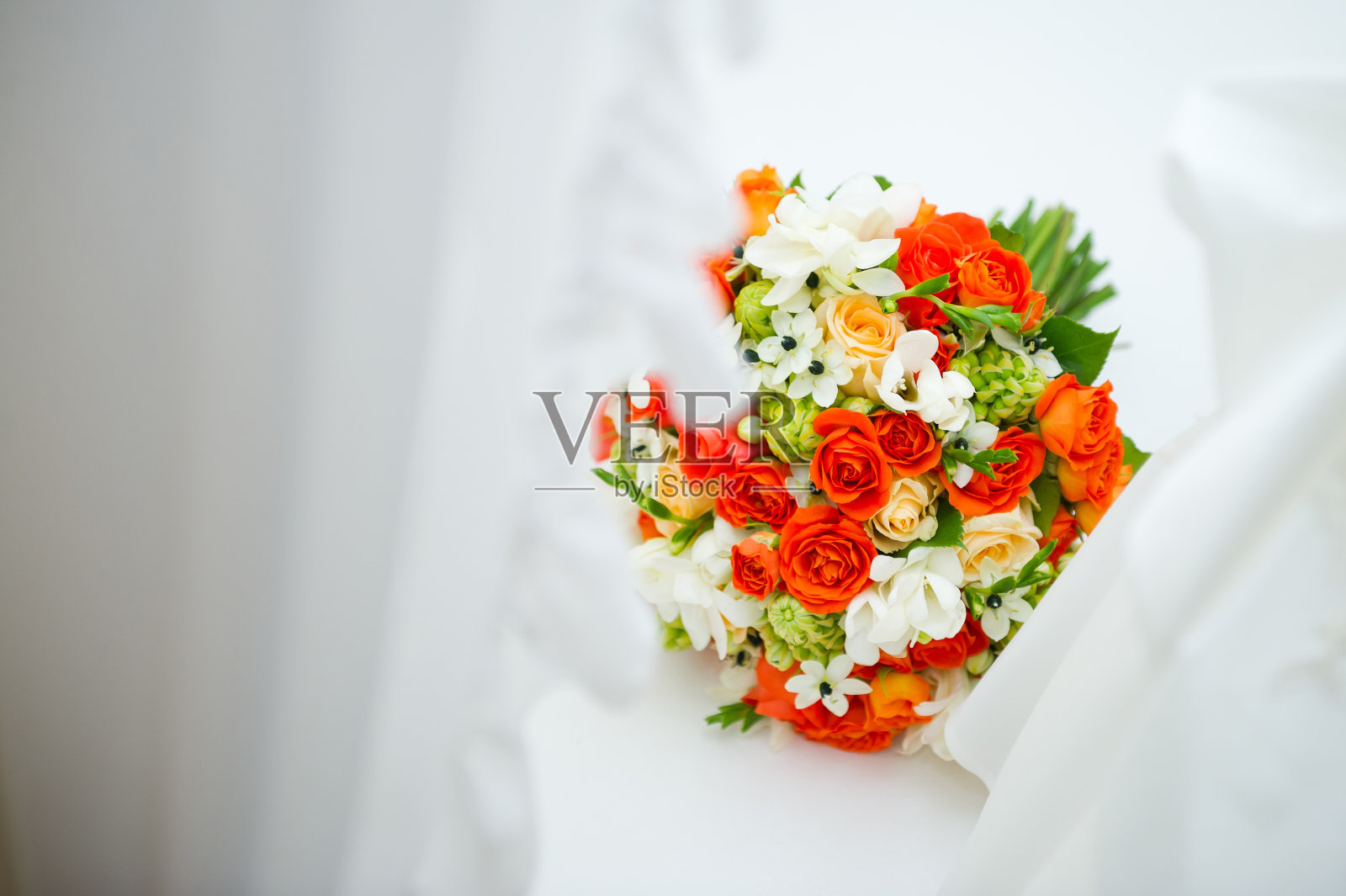 一束鲜艳的花束躺在窗台上，微微地覆盖着白色的窗帘照片摄影图片