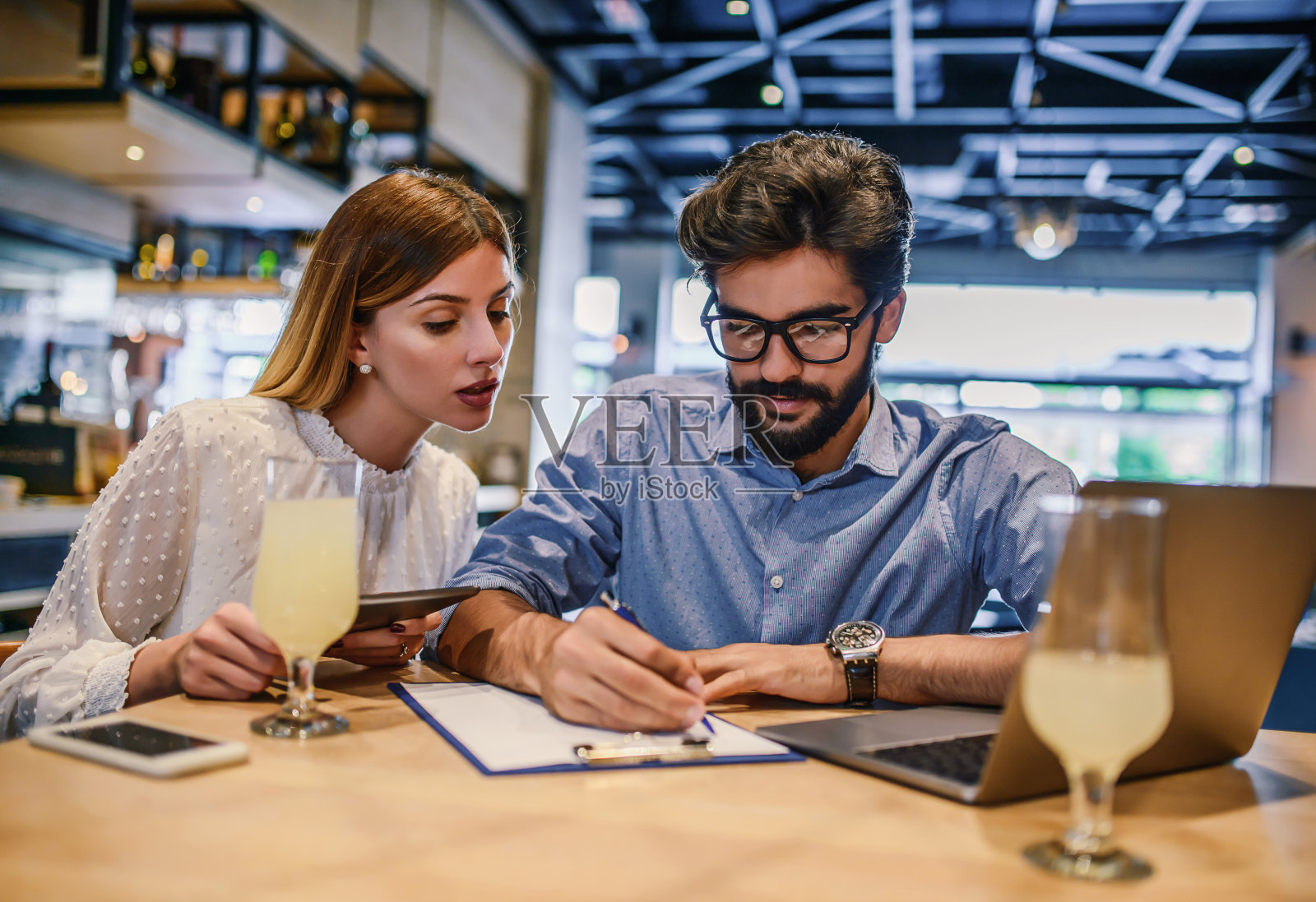 团队合作精神。年轻的学生坐在咖啡馆里用笔记本电脑做笔记。商业、教育、生活理念照片摄影图片