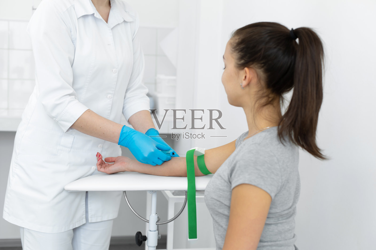诊所的一名护士将一根导管插入静脉，为一名年轻女孩进行血液检测照片摄影图片