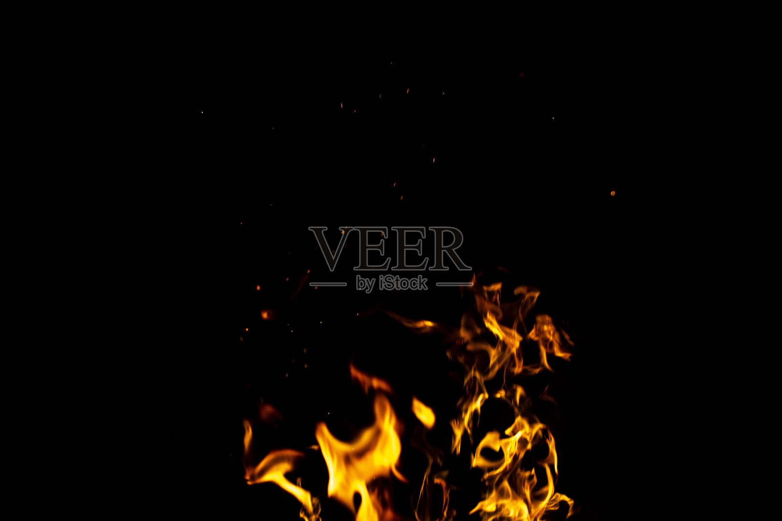 燃烧着的红色炽热的火花从夜空中的大火中飞出来。以火、光和生命为主题的美丽抽象背景。照片摄影图片