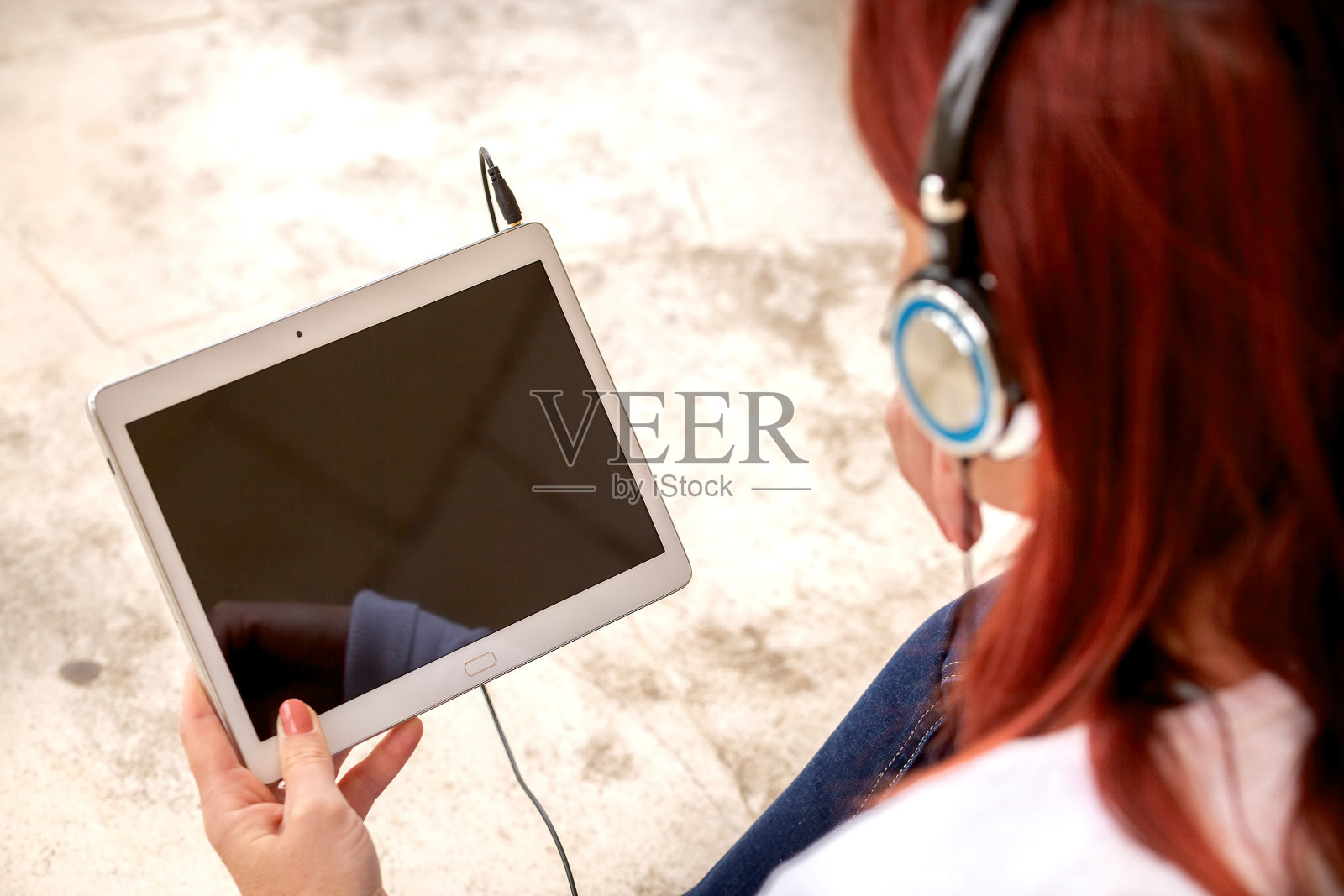 可爱的微笑红发女人坐在地板上听音乐或看电影的触摸板照片摄影图片