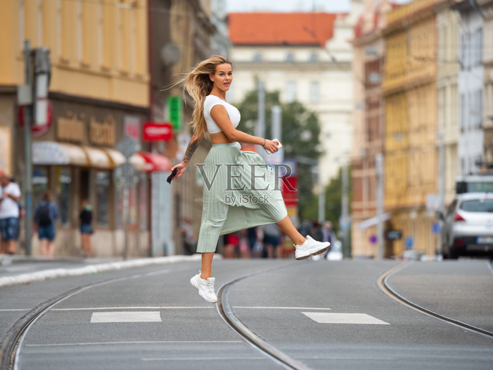金发酷女人过马路，跳跃，盘旋，查看手机照片摄影图片