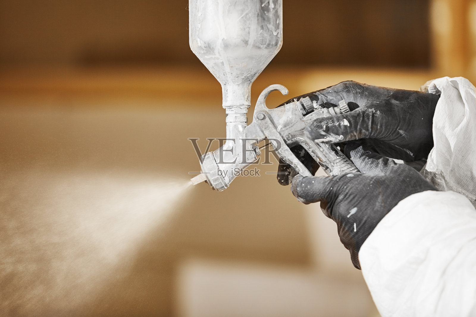 一个人用枪向木头喷射的特写画面。照片摄影图片