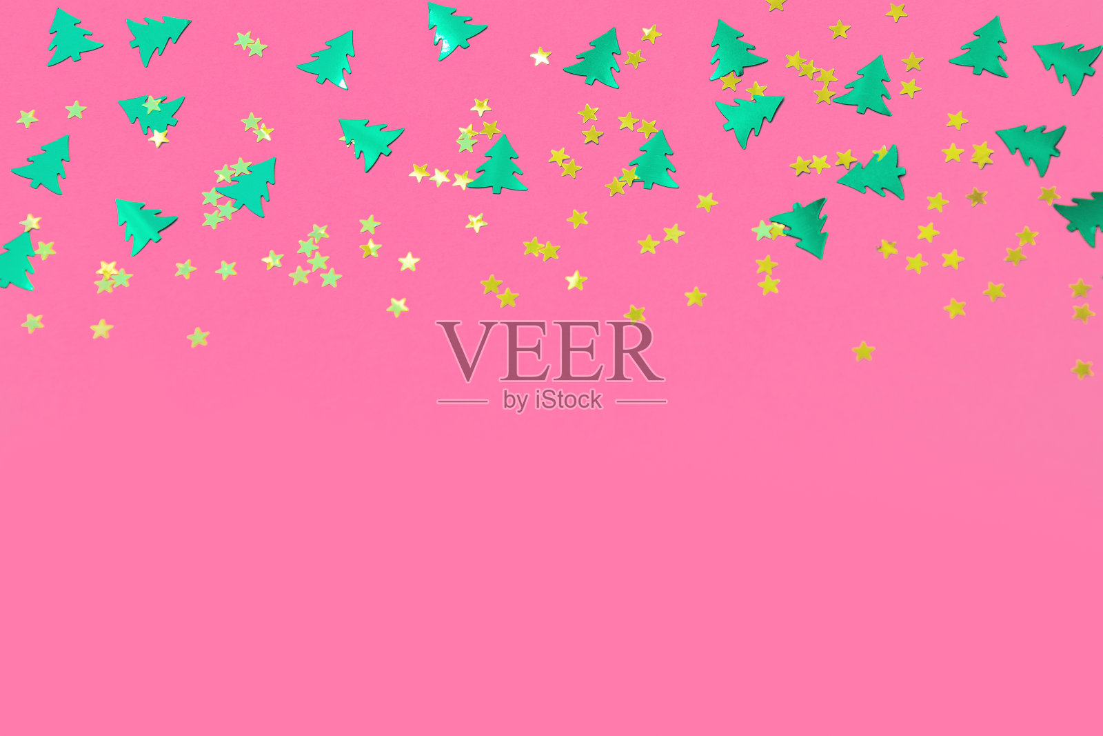 绿色的圣诞树和金色的星星点缀在粉红色的背景上照片摄影图片