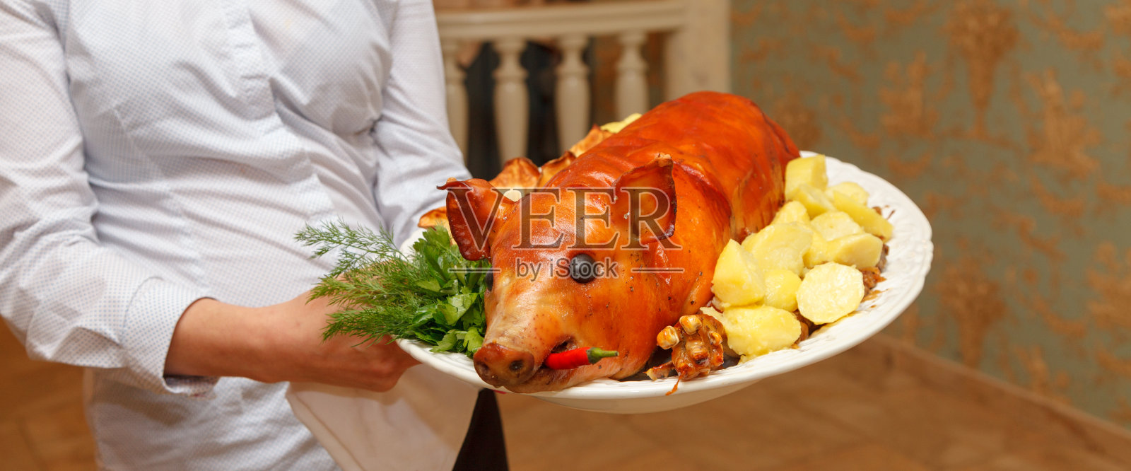 服务员端着一个白色的盘子，上面有煮土豆，新鲜的欧芹，莳萝和红辣椒照片摄影图片