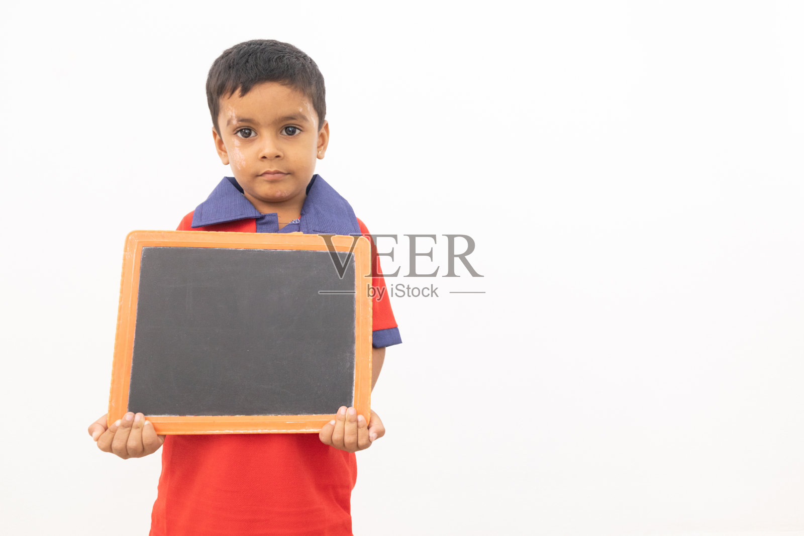 在孤立的背景下，一个小男孩拿着黑色的石板进行儿童抗议的概念。照片摄影图片