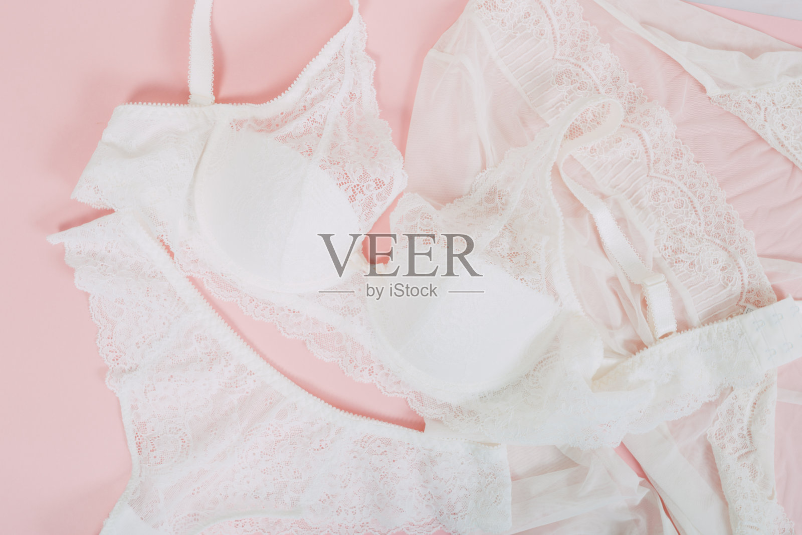 粉色背景上有花边的白人女性内衣。whitebra和短裤。副本的空间。美丽，时尚博主概念。情人节诱惑的浪漫内衣。照片摄影图片