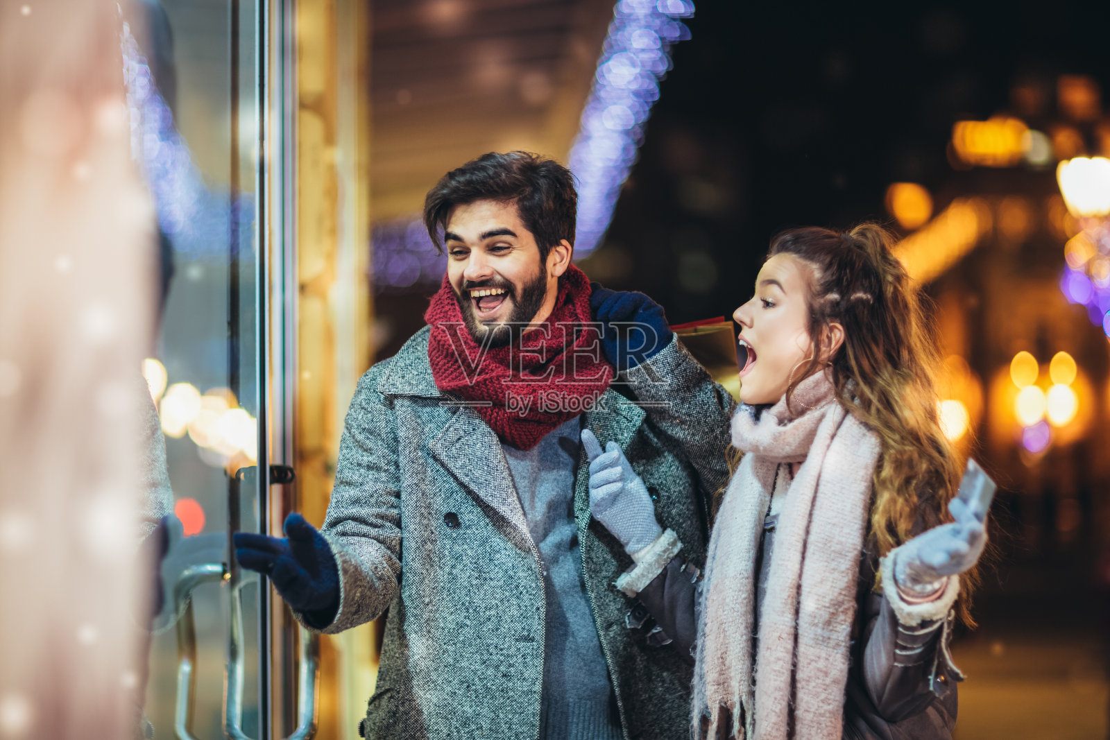 一对夫妇用信用卡做圣诞彩灯背景，在晚上走在城市里照片摄影图片