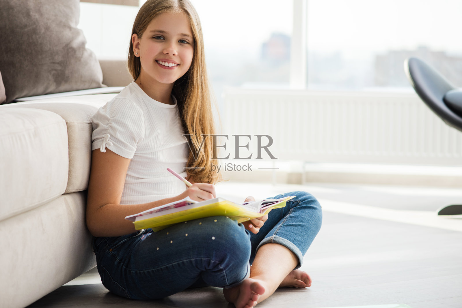 可爱的女学生坐在地板上写笔记本照片摄影图片