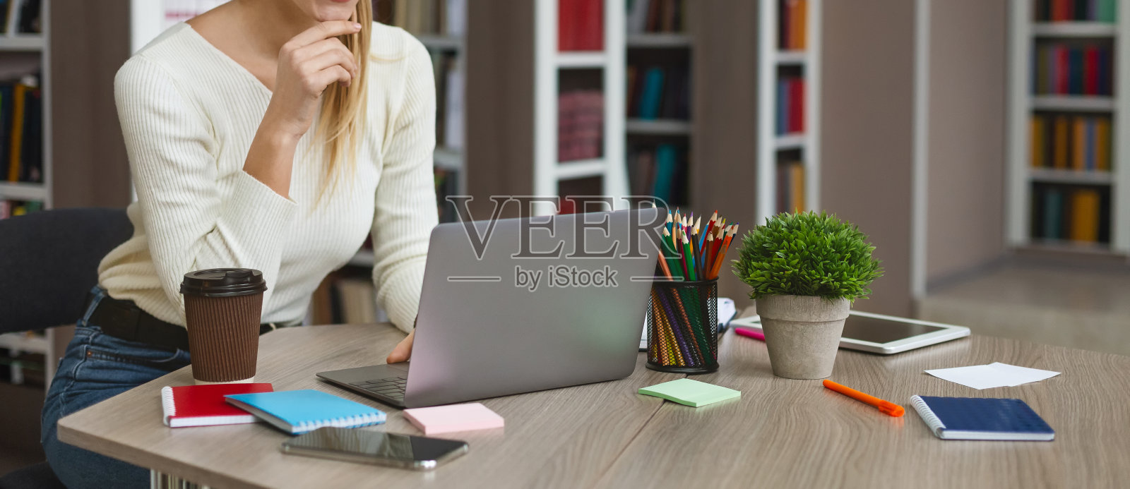 年轻女学生坐在图书馆的笔记本电脑前照片摄影图片
