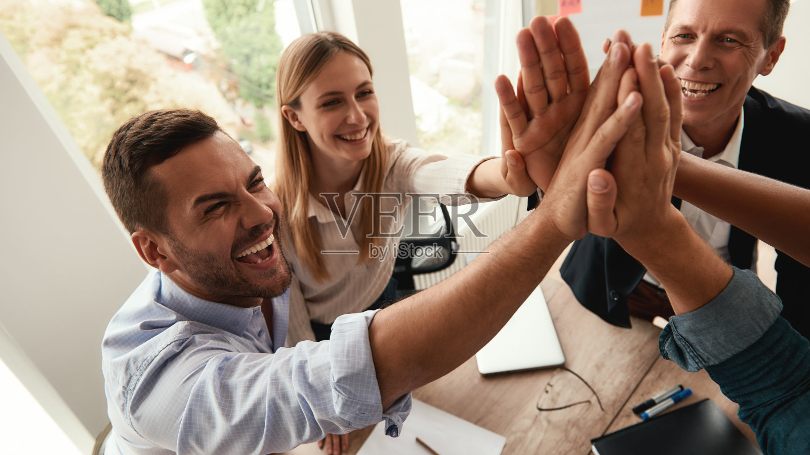 成功的团队!商务人士在现代办公室里一起工作时互相击掌和微笑照片摄影图片