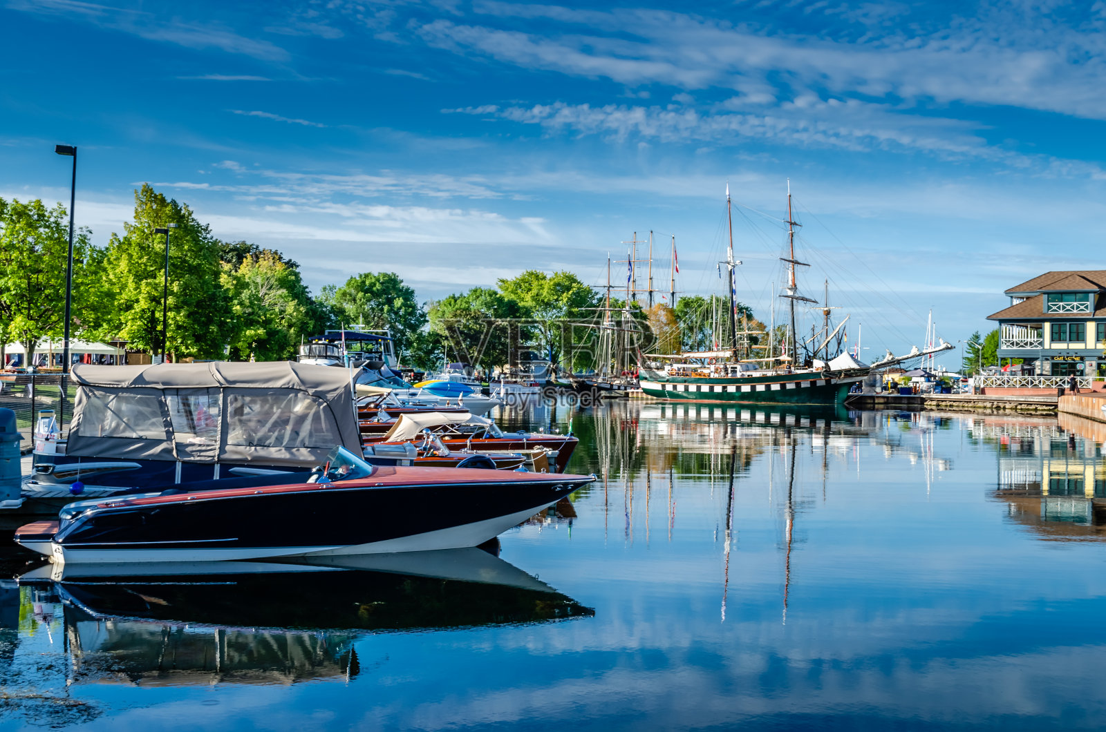 各种各样的船和他们的倒影在一个夏天的港口与一个轻云的蓝天。照片摄影图片