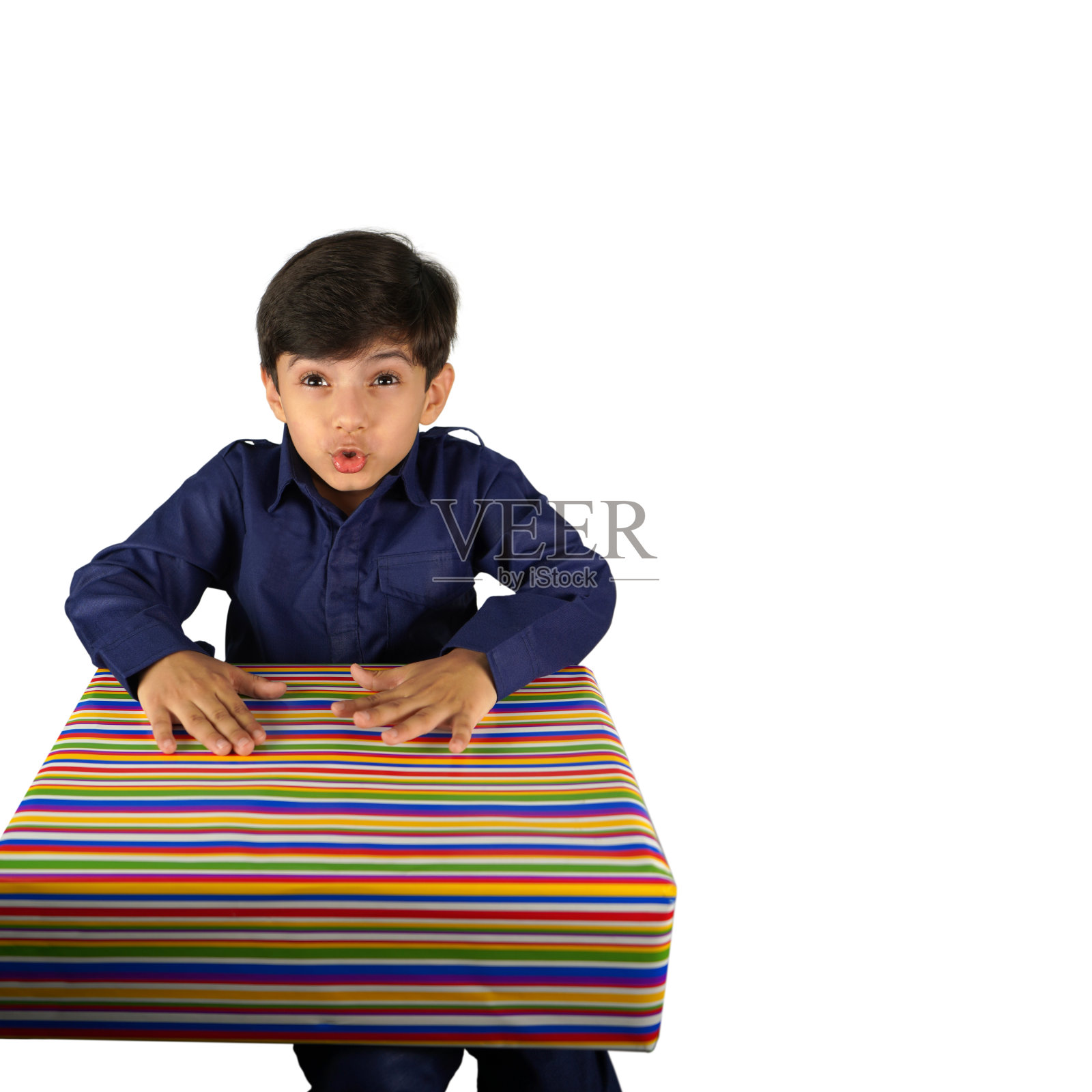 一个兴奋的印度亚裔小男孩撅着嘴，撅着嘴，撅着嘴拿着一件礼物，在白色的背景下孤立无间照片摄影图片