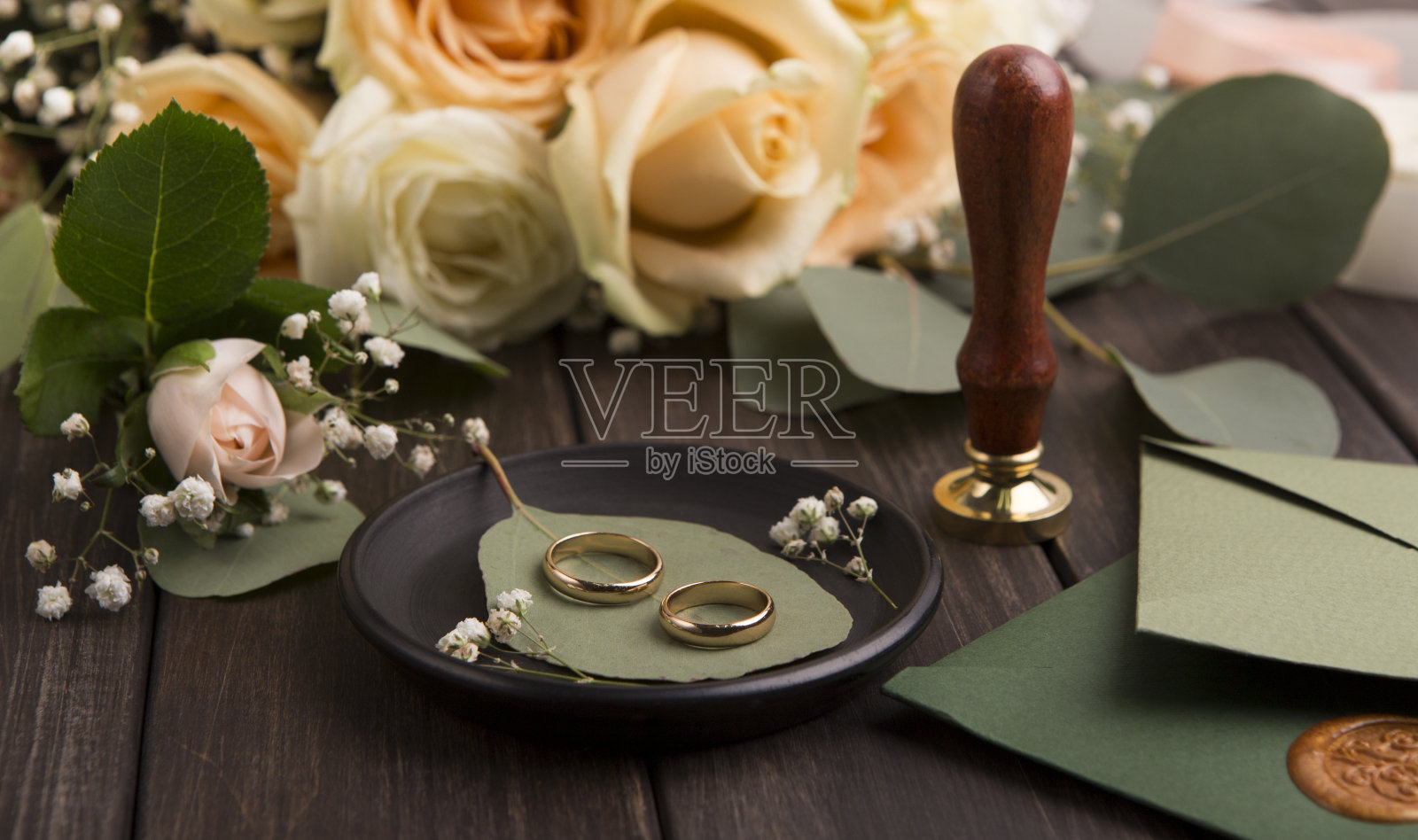 一对金色的结婚戒指，打印和请柬在木头上照片摄影图片