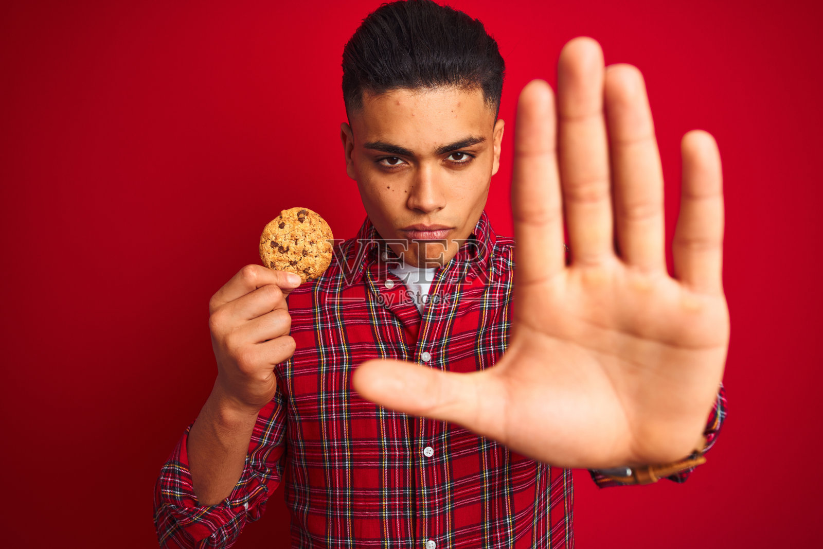 拿着饼干的年轻巴西男人，做出停止手势照片摄影图片