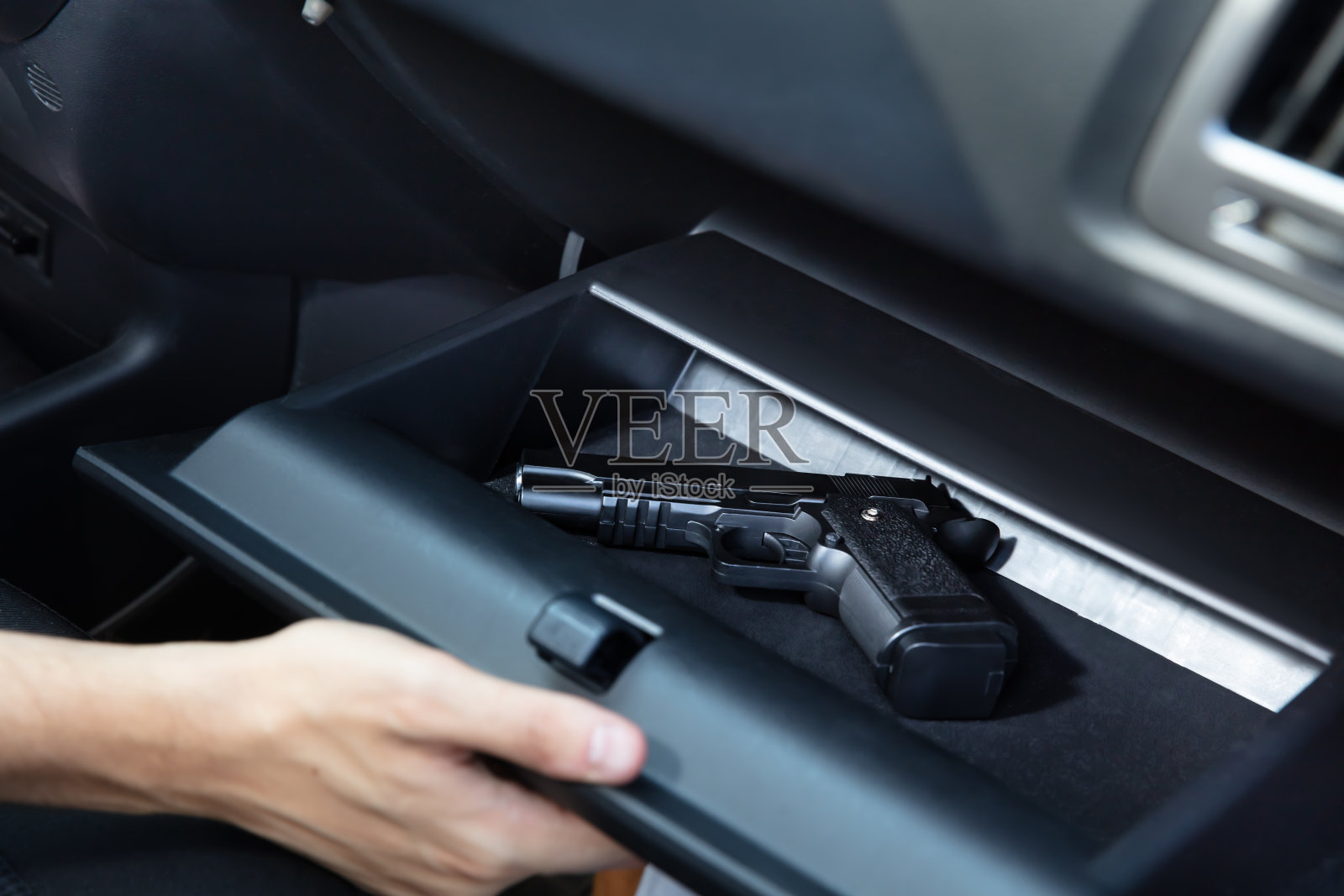 司机从手套箱里拿出手枪照片摄影图片