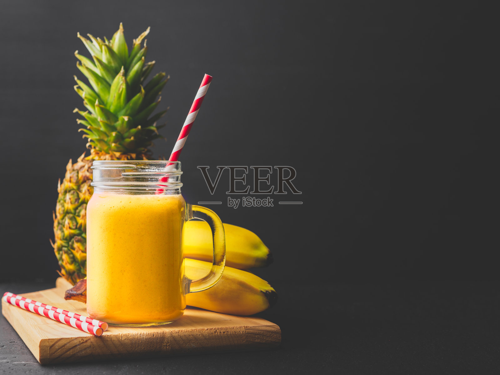 菠萝香蕉奶昔装在玻璃罐里，用一根吸管照片摄影图片