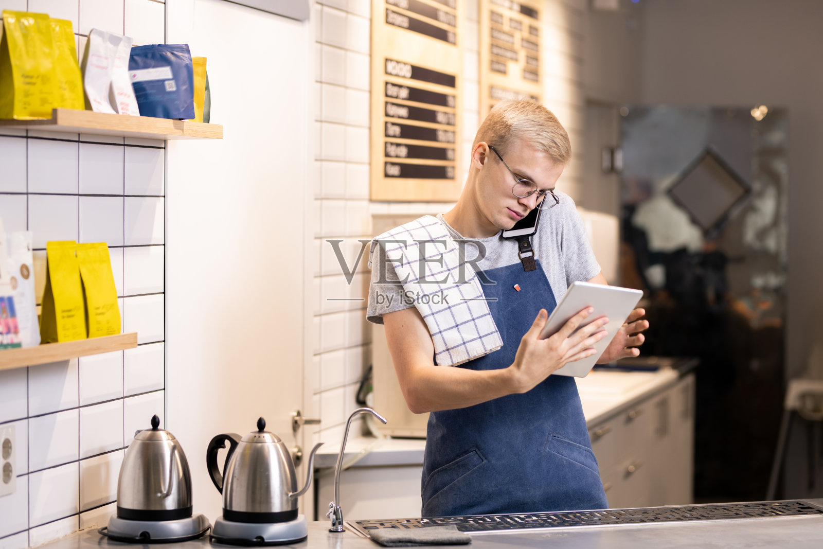 忙碌的年轻移动咖啡师在网上和电话上为客户点单照片摄影图片